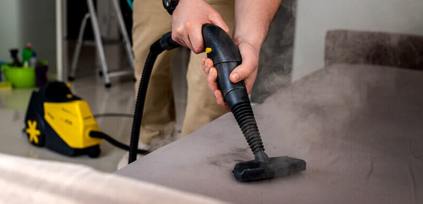Upholstered sofa being cleaned with a handheld upholstery tool